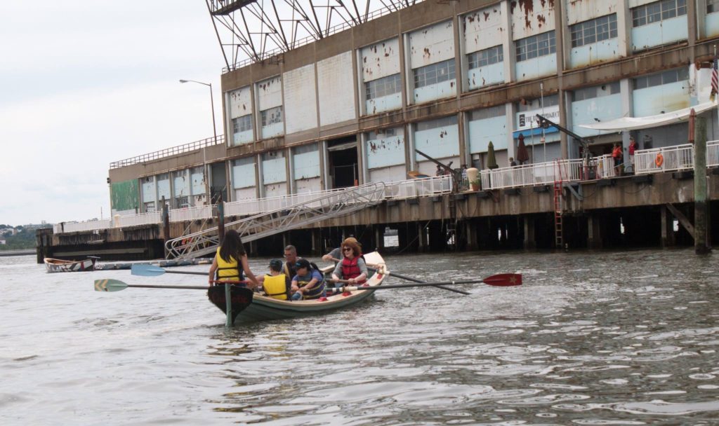 six people in a rowboat approach a ladder